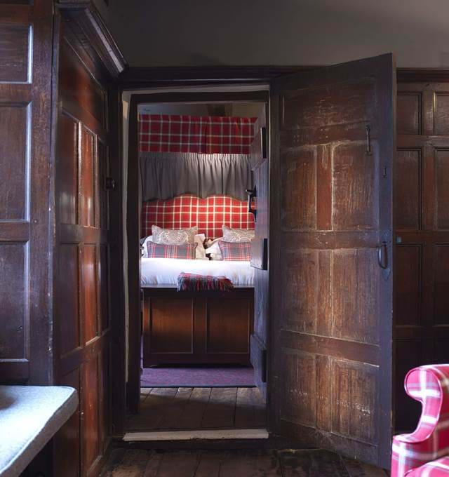 A classic four-poster bed with plaid details and warm lighting.