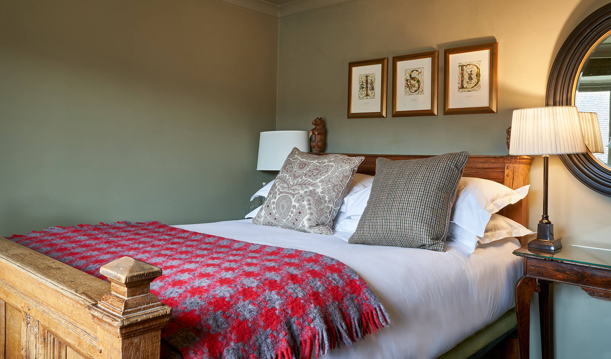A rustic bedroom with patterned pillows, a red check blanket, and a wooden headboard.