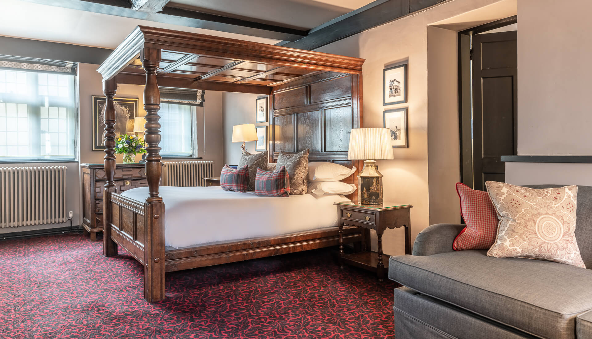Bedroom with plaid accents, armchair, and four posters wood bed.
