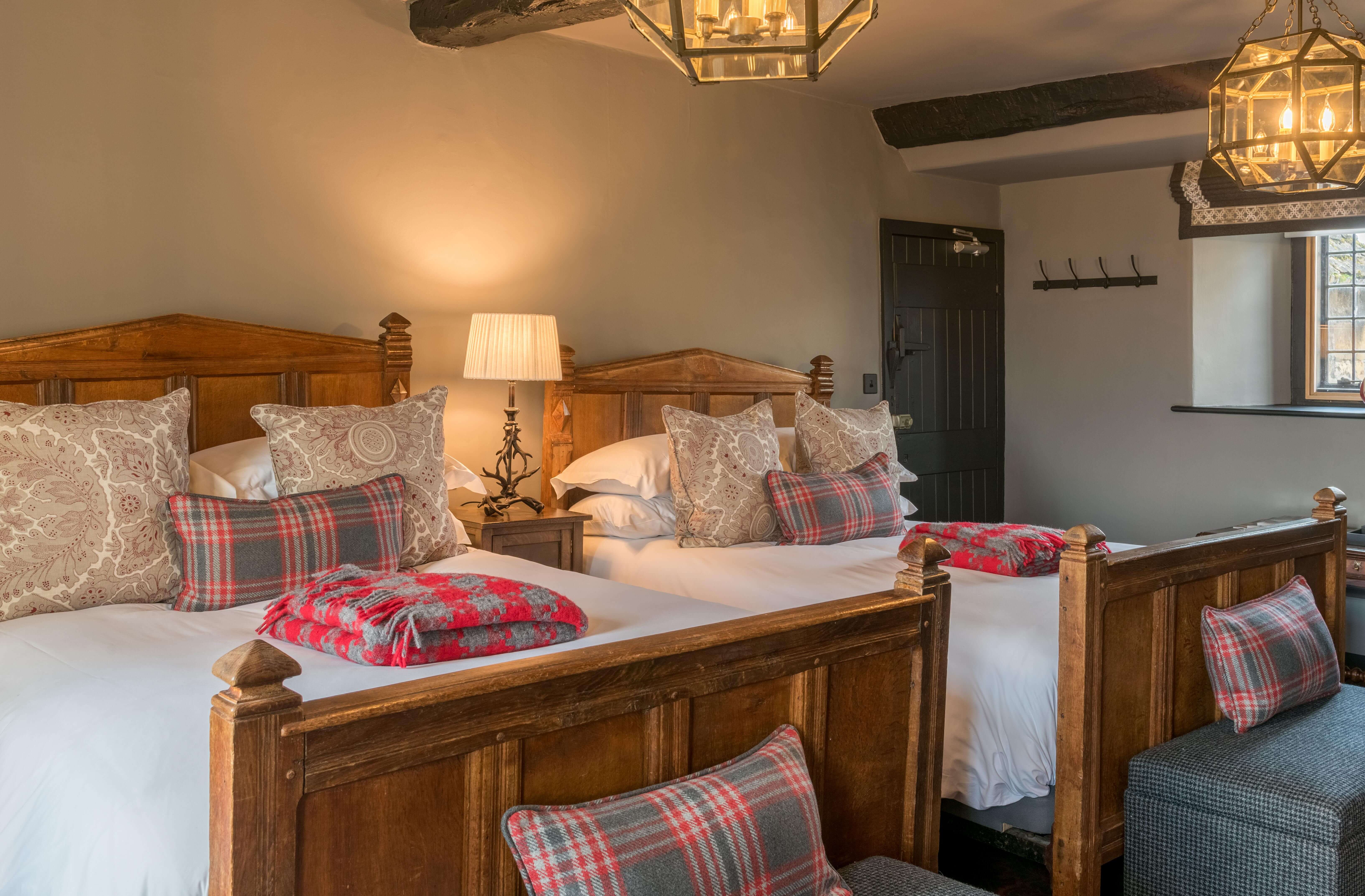 A cosy twin room with two twin beds next to each other and plaid cushions on the bed.