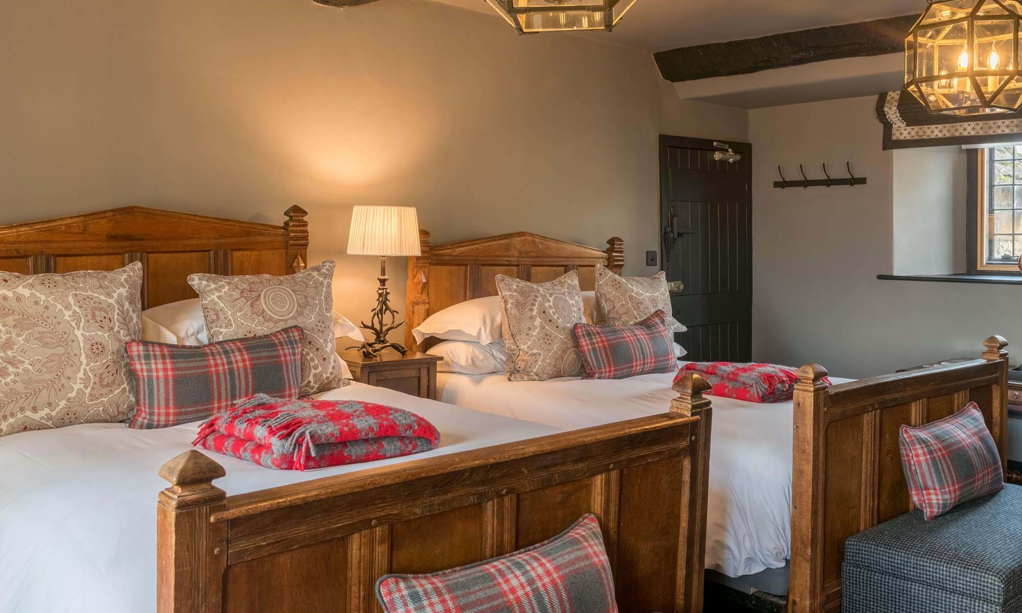 A cosy twin room with two twin beds next to each other and plaid cushions on the bed.