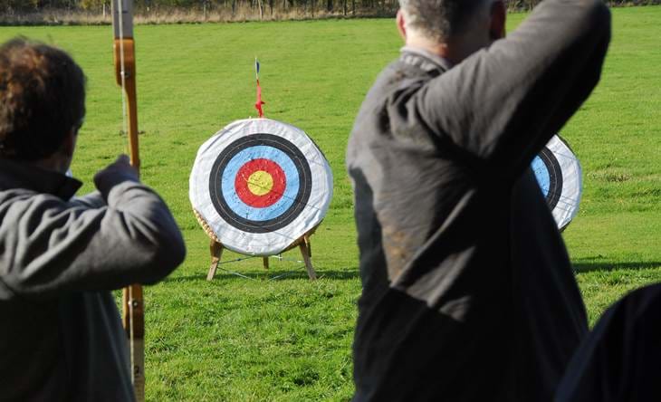 People practicing archery outdoors