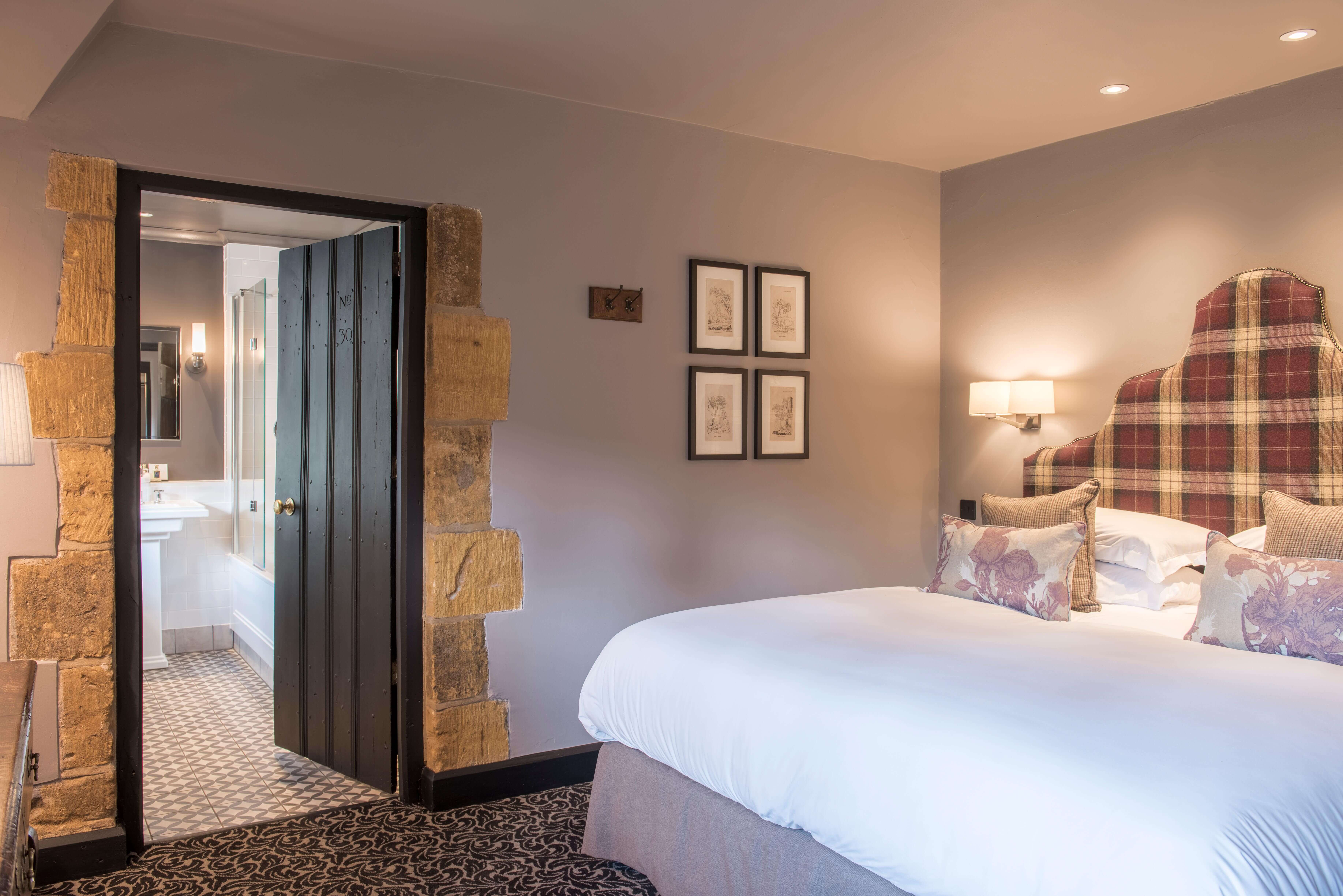 Cosy classic bedroom, with white bed linen, wall art, and door opening to the en-suite.