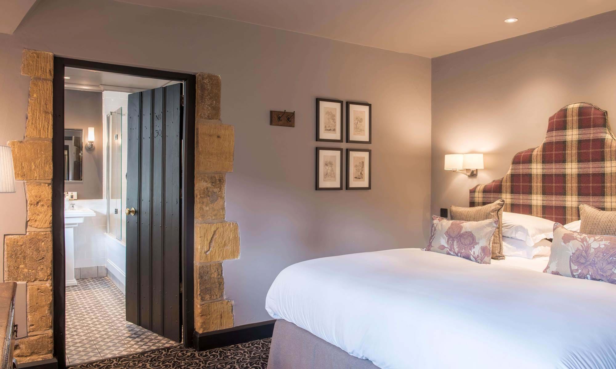 Cosy classic bedroom, with white bed linen, wall art, and door opening to the en-suite.