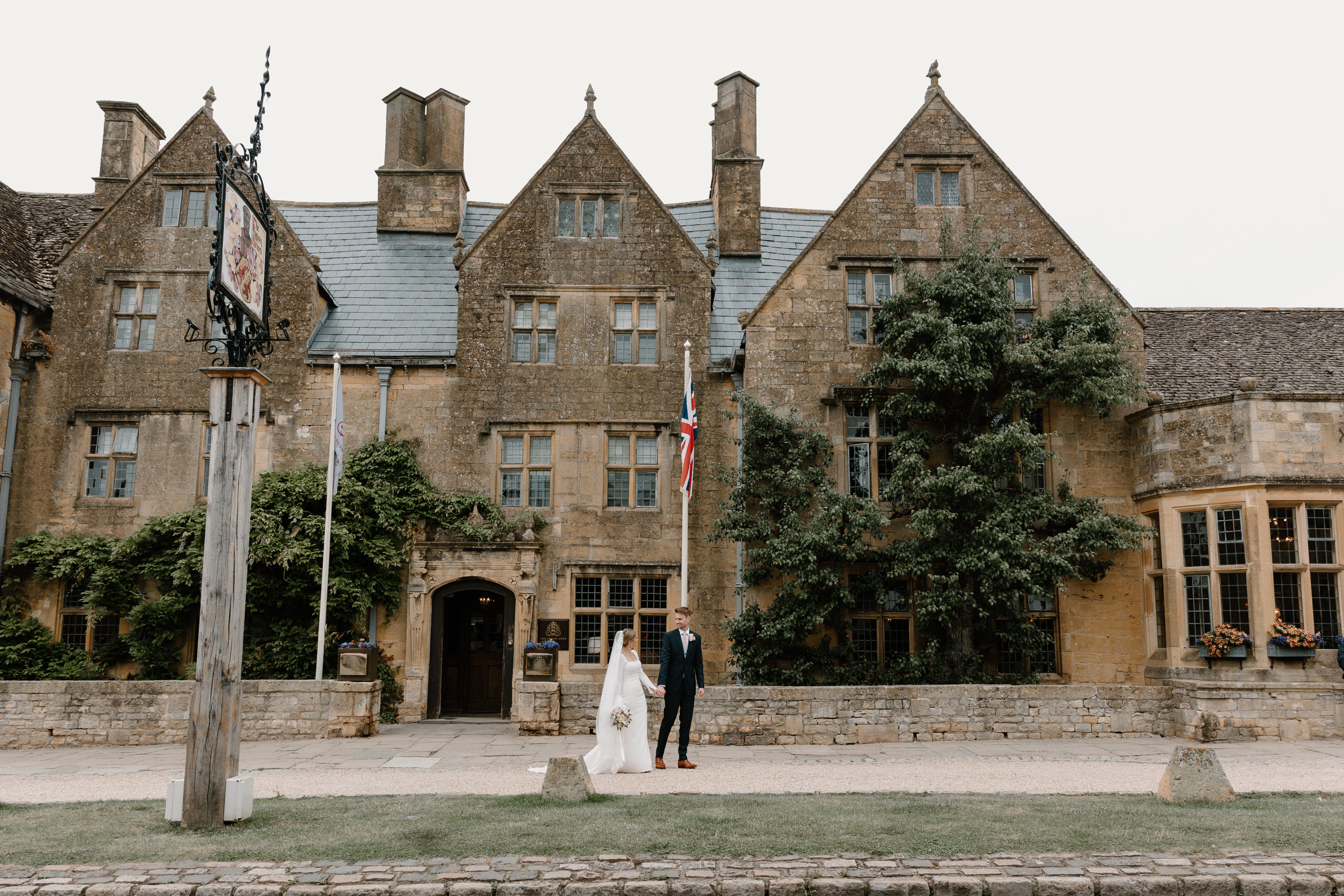 Happy couple on their wedding day posing in front of The Lygon Arms